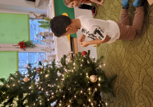 Chłopiec zawiesza ozdobę na choinkę