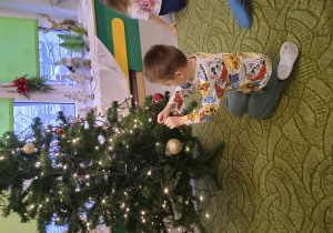 Chłopiec zawiesza ozdobę na choinkę