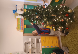 Chłopiec zawiesza ozdobę na choinkę