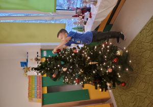 Chłopiec zawiesza ozdobę na choinkę
