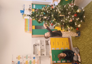 Chłopiec zawiesza ozdobę na choinkę