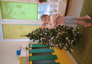 Dziewczynka zawiesza ozdobę na choinkę