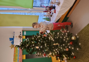 Dziewczynka zawiesza ozdobę na choinkę