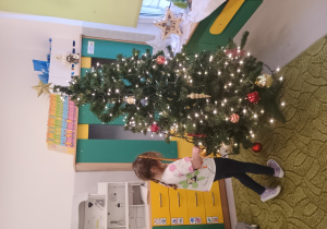 Dziewczynka zawiesza ozdobę na choinkę