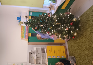 Dziewczynka zawiesza ozdobę na choinkę
