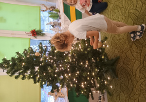 Dziewczynka zawiesza ozdobę na choinkę