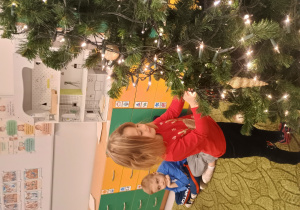 Dziewczynka zawiesza ozdobę na choinkę