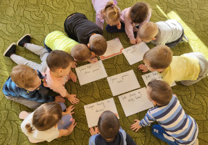 Dzieci siedzą dookoła kartek z pytaniami