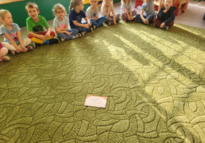 Dzieci siedzą w kole, zgłaszają się do odpowiedzi