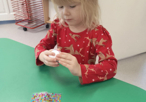 Dziewczynka przykleja diamenciki na bombkę