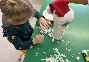 Dziewczynka przykleja kawałki bibuły do rolki