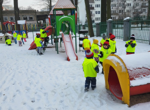 Dzieci bawią się na śniegu w ogrodzie przedszkolnym