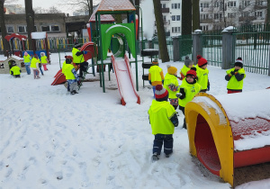 Dzieci bawią się na śniegu w ogrodzie przedszkolnym