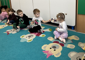 Dzieci podają sobie zdjęcia po kolei i je oglądają