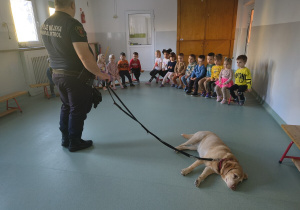 Dzieci patrzą na strażnika miejskiego i psa