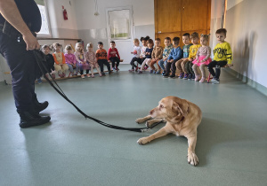 Dzieci siedzą i słuchają strażnika miejskiego