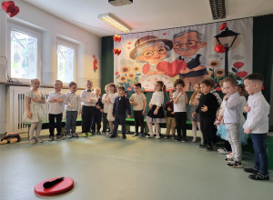 Dzieci stoją w półkolu, śpiewają piosenkę