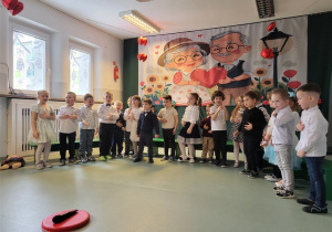 Dzieci stoją w półkolu, śpiewają piosenkę