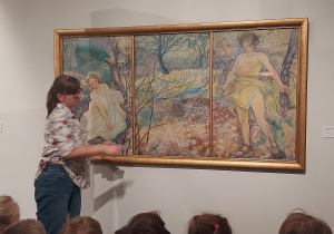Prowadząca pokazuje obraz o pastelowych barwach - pora roku: wiosna