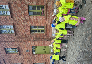 Dzieci stoją na tle budynku z cegły