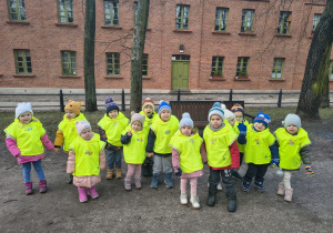 Dzieci stoją na tle budynku z cegły