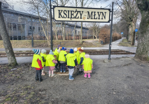 Dzieci stoją pod napisem Księży Młyn
