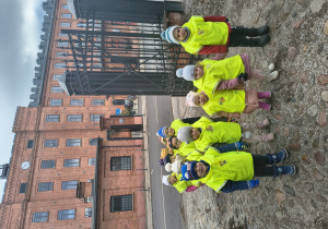 Dzieci stoją na tle budynku z cegły