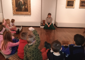 Dzieci słuchają opowiadania prowadzącej warsztaty