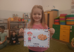 Dziewczynka prezentuje obrazek pączków i przysmaków w innych krajach