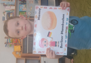 Chłopiec prezentuje obrazek pączków i przysmaków w innych krajach