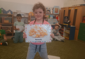 Dziewczynka prezentuje obrazek pączków i przysmaków w innych krajach