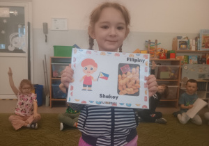 Dziewczynka prezentuje obrazek pączków i przysmaków w innych krajach