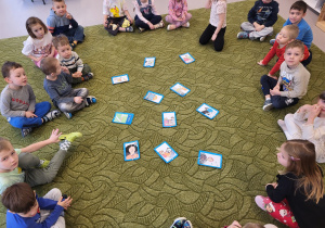 Dzieci siedzą w kole, po środku leżą obrazki