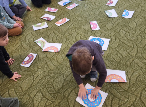 Dzieci siedzą w kole, chłopiec łączy połowy pączków