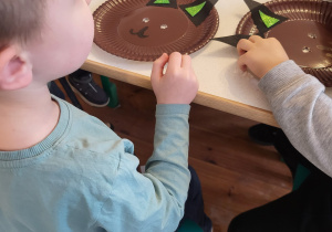 Chłopiec siedzi przy stoliku z papierowym talerzykiem