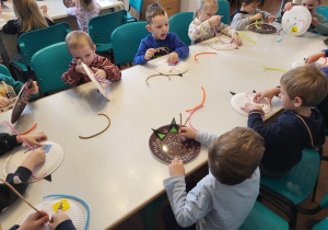 Dzieci nawlekają wąsy papierowym kotkom