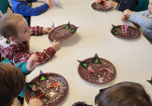 Dzieci nawlekają wąsy papierowym kotkom