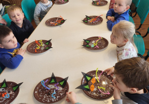 Dzieci siedzą przy stolikach i czekają na dalsze instrukcje