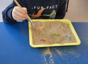 Chłopiec pędzelkiem odkopuje dinozaury