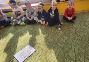 Dzieci w opaskach siedzą na dywanie