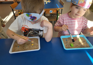 Dzieci pędzelkiem odkopują dinozaury z piasku