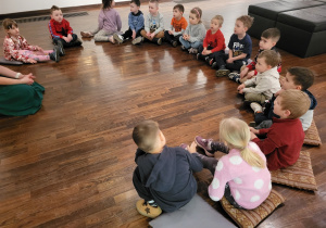 Dzieci siedzą na poduszkach w półkolu