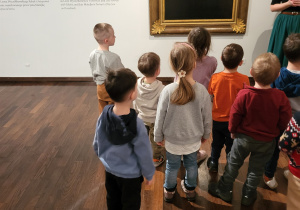 Dzieci oglądają obraz kobiety w czarnym ubraniu