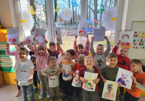 Dzieci pozują z namalowanymi przez siebie portretami