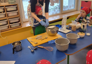 Chłopiec z nauczycielką przesiewają mąkę