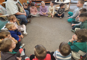 Dzieci siedzą w kole na dywanie