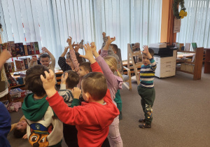 Dzieci stoją, unoszą ręce do góry