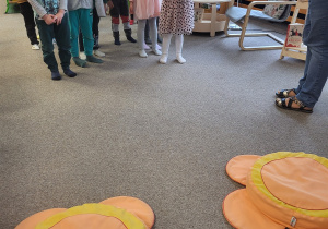 Dzieci stoją w dwóch rzędach, patrzą na bibliotekarkę