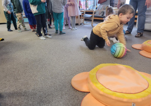 Chłopiec turla piłkę do poduszek - kwiatków