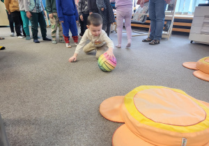 Chłopiec turla piłkę do poduszek - kwiatków